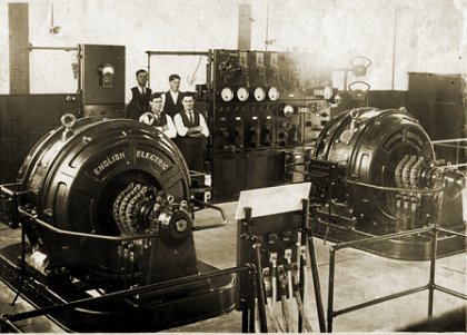 Interior of Ascot Vale substation circa 1925, showing two English 
            Electric rotary converters, the control panel and a group of four 
            substation attendants. Photograph TMSV